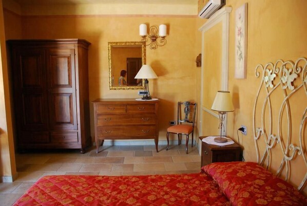 A bedroom with a bed, a dresser, a chair, and a nightstand with a lamp.