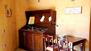 Una cocina compacta con armarios de madera, una estufa y una mesa de comedor con sillas.