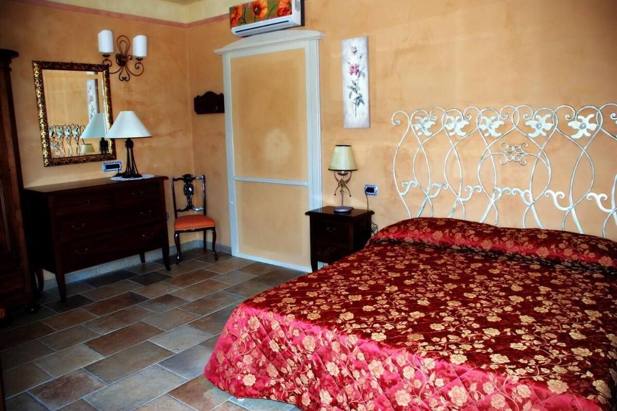 A bedroom with a large bed, a dresser, a chair, a wardrobe, and a mirror.