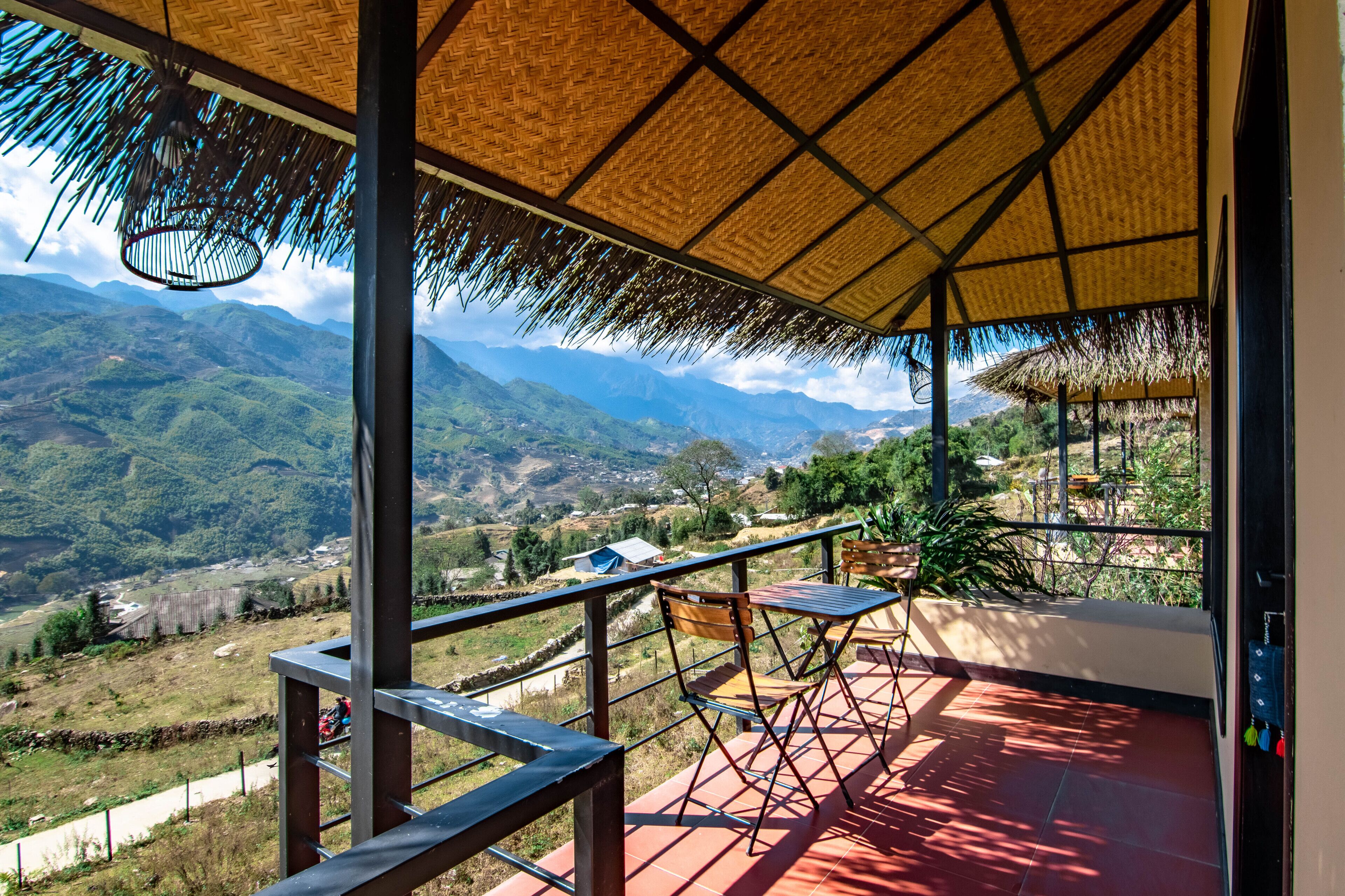 Un balcon doté d’un toit de chaume, offrant une vue sur un paysage montagneux.