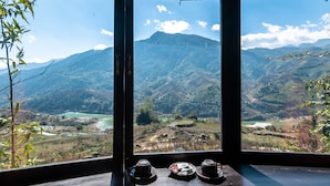 Habitación con vistas a montañas y un río. Hay dos tazas sobre la mesa.