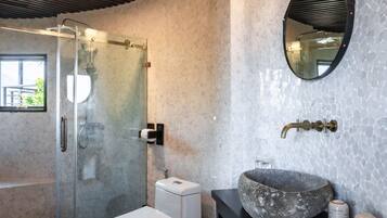Une salle de bain moderne avec une douche à parois de verre, des toilettes blanches, un lavabo en pierre et un meuble-lavabo noir.