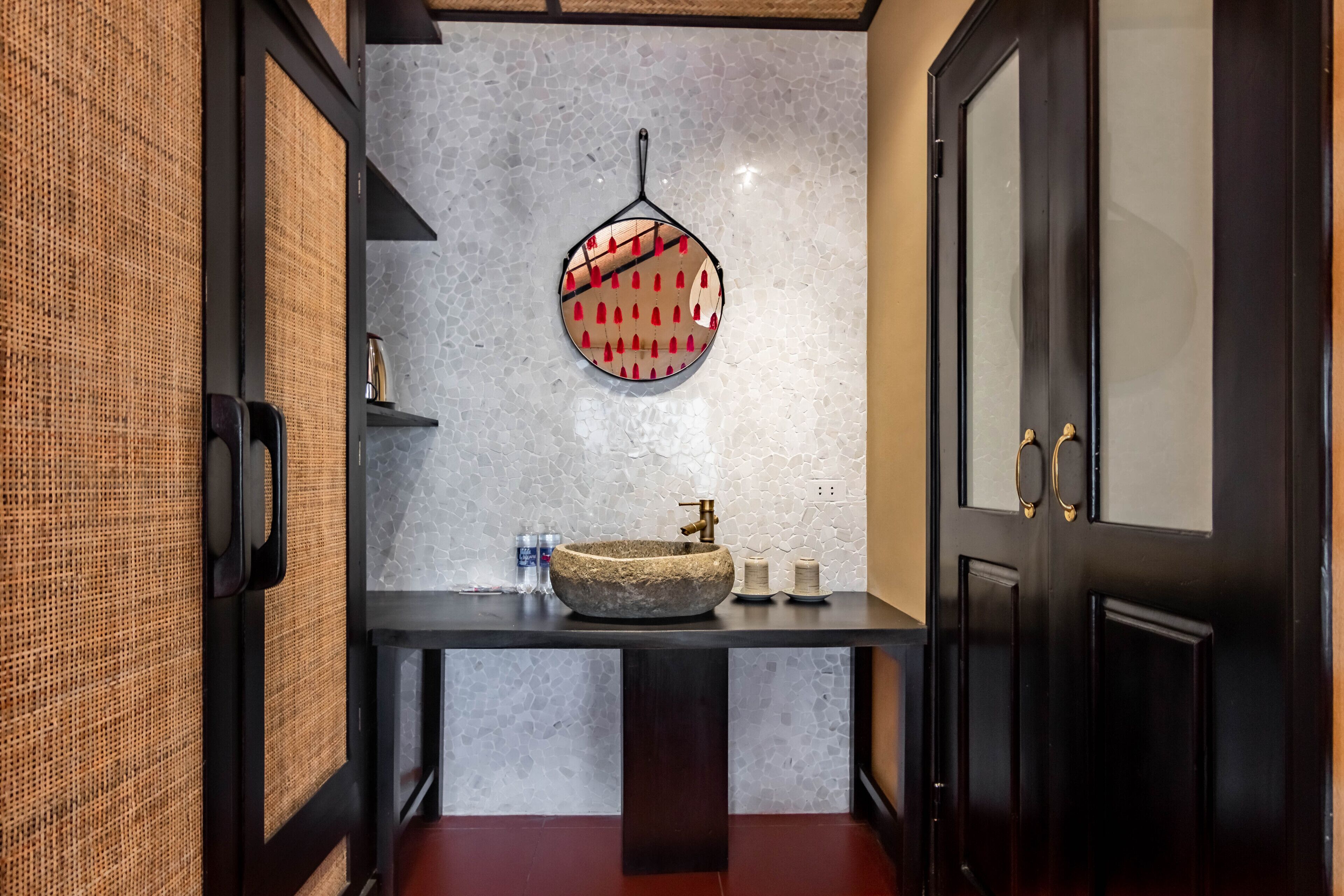 Une salle de bain moderne avec un lavabo en pierre, un élément décoratif suspendu et un mur à texture.
