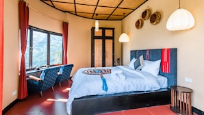 Un dormitorio con una cama grande, un comedor con sillas, un ventanal con cortinas y un techo con diseño tejido.