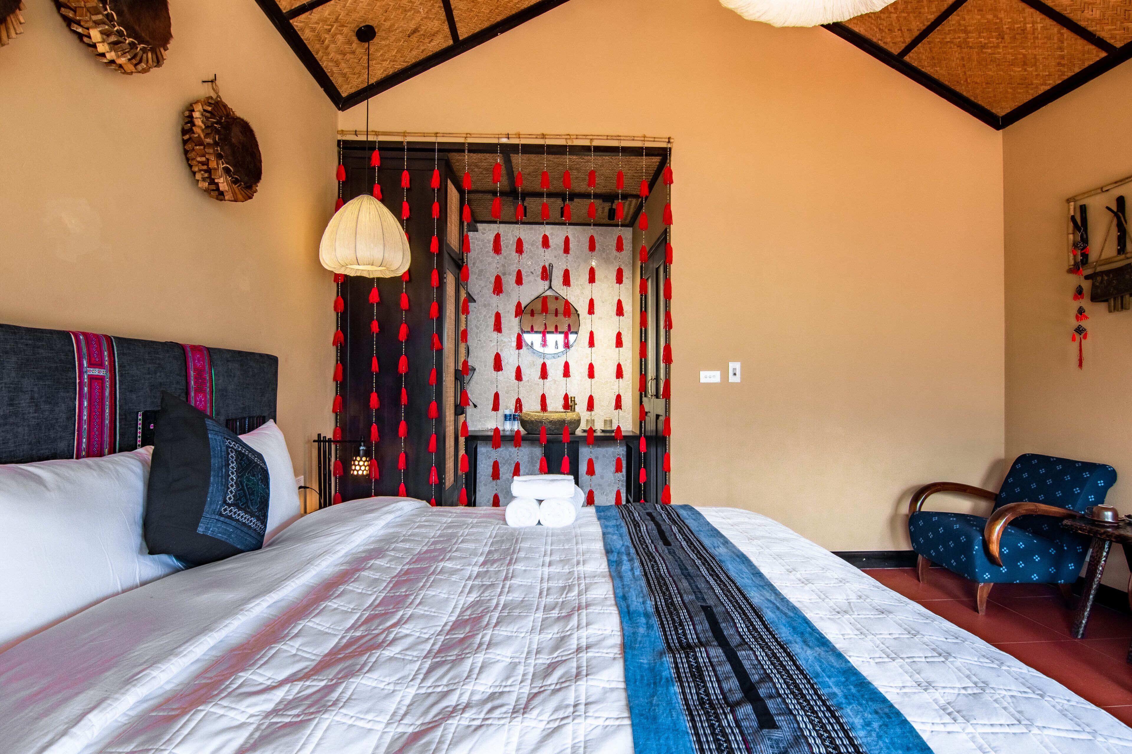 A room with a bed, a chair, a hanging light fixture, and a decorative wall.