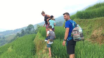 A group of people standing on a grassy hill with a mountainous background.