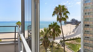 A balcony with a view of a beach, palm trees, and a cityscape. - Welgelegen 608 (Cape Town)