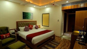 A hotel room with a bed, a chair, a desk, and a ceiling fan.