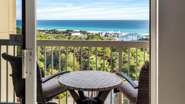 A balcony with a view of the ocean and a white house in the background. - Summit at Tops`l 810 - Beautiful Gulf Views! (Miramar Beach)