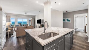 A modern kitchen with granite countertops, a stainless steel sink, and dark cabinetry. - Summit at Tops`l 810 - Beautiful Gulf Views! (Miramar Beach)
