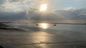 A beach with the sun setting over the water, boats, and a clear sky. - PORT-DES-BARQUES (Port-des-Barques)