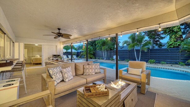 A modern outdoor living area with a pool, seating, and a ceiling fan. - Open Labor Day Weekend |HTD Pool | 6 TVS | 2 King beds (Bradenton)