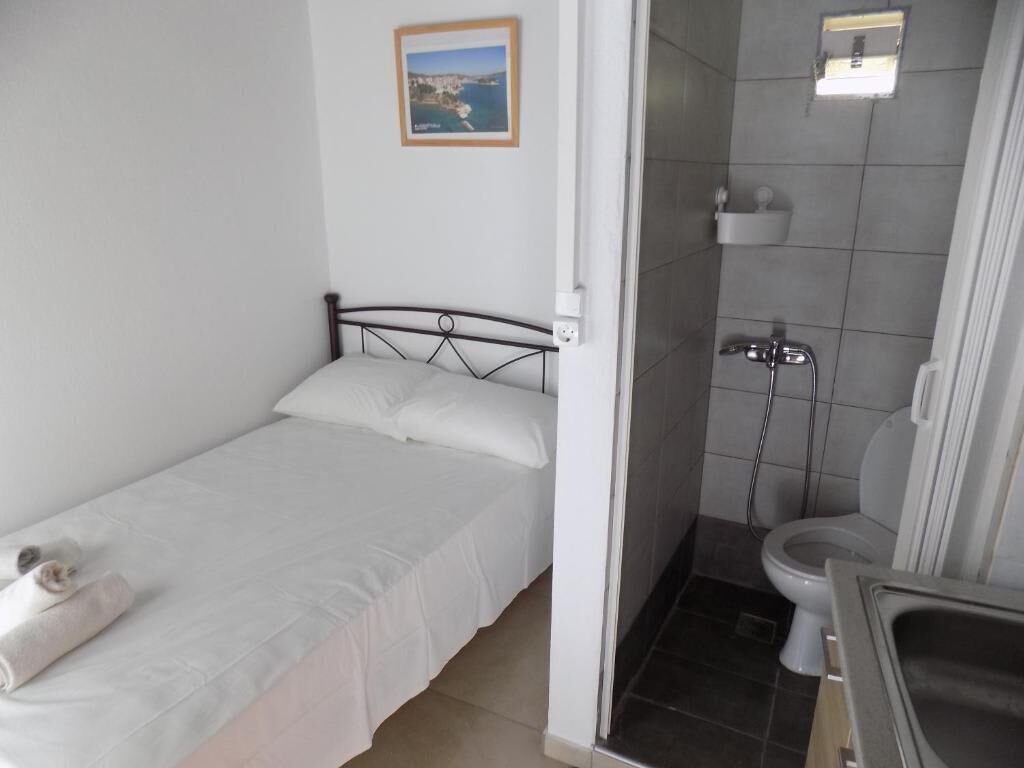 Una stanza piccola e pulita con un letto singolo, una doccia e un bagno.