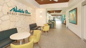 A modern interior with a stone wall, a seating area with a bench and chairs, a ceiling fan, and a framed picture on the wall.