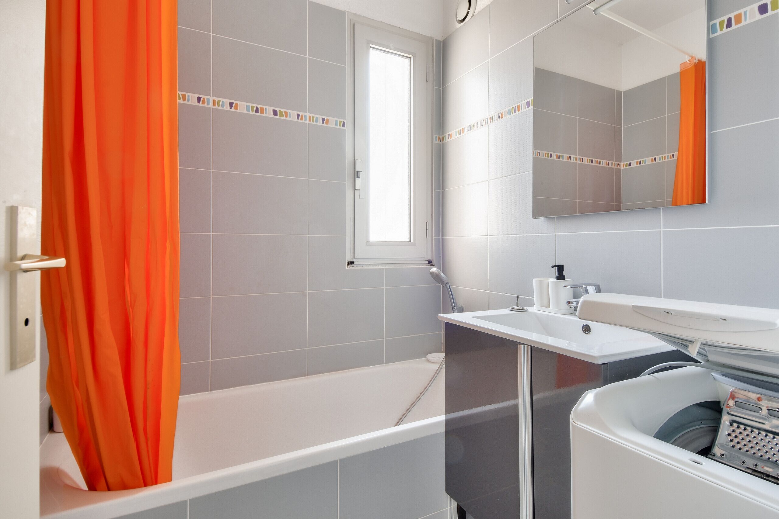 Un baño con bañera, lavamanos, espejo y ventana.