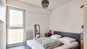 Una camera da letto con un letto, un comodino, uno specchio, una lampada e una finestra.