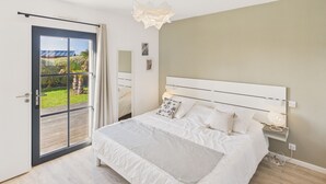 A bedroom with a large bed, a sliding glass door to a balcony, a white headboard, and a bedside table with a lamp. - Surf & swimming – 300 m from Pors Carn beach (Penmarch)