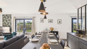 A modern dining area with a long table set for a meal, a fruit basket, and a loaf of bread. - Surf & swimming – 300 m from Pors Carn beach (Penmarch)
