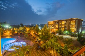 A hotel with a swimming pool, outdoor seating area, and a view of the city at night. - HOTEL LA VENA (Kampala)