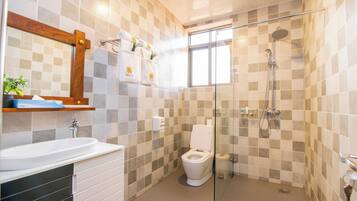 A modern bathroom with a glass-enclosed shower, a white sink, and a toilet.