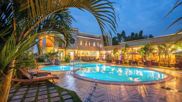 Un espace piscine avec des chaises longues et un bâtiment doté de nombreuses fenêtres et d’un balcon.