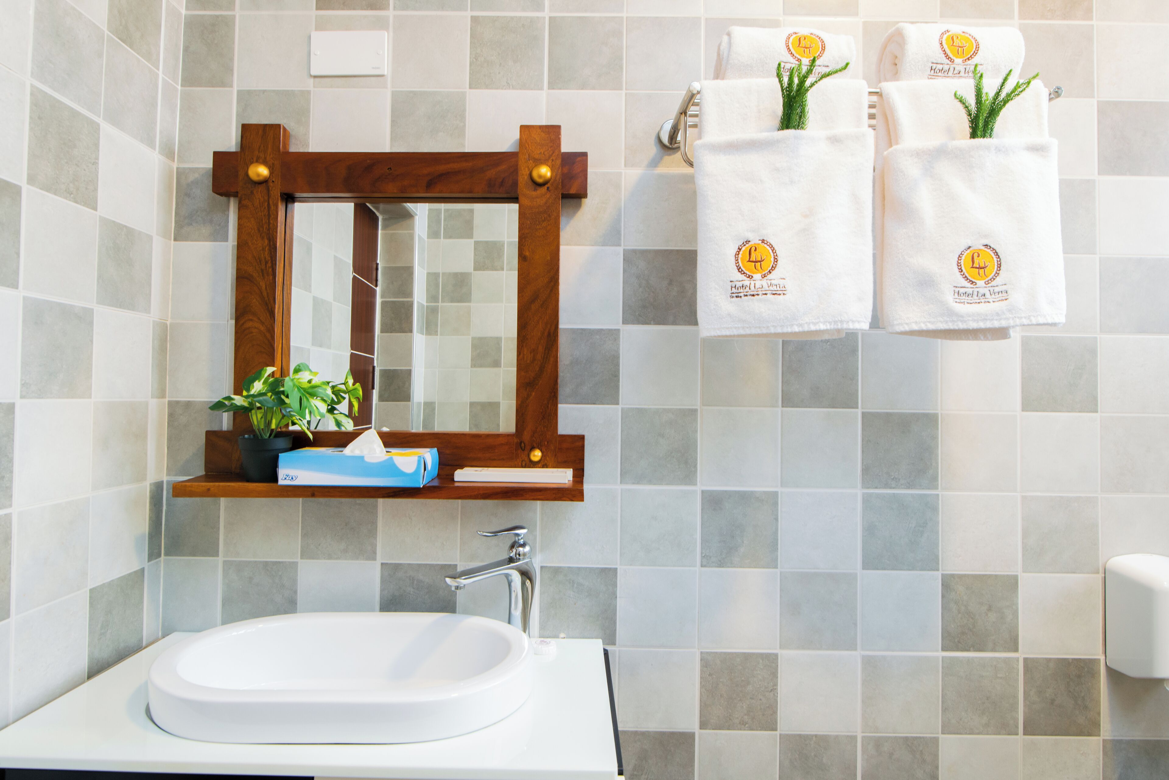 A bathroom with a white sink, a wooden-framed mirror, and two towels hanging on the wall.