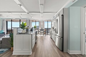 A modern kitchen with a central island, stainless steel appliances, and a view to the outside.