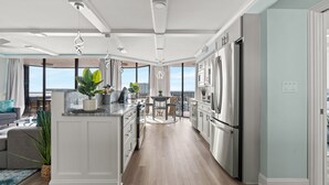 A modern kitchen with a central island, stainless steel appliances, and a view to the outside. - Completely Renovated Ocean View Unit + Free Attraction Tickets! (Myrtle Beach)