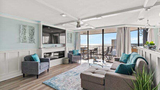 A spacious living room with a sofa, armchairs, and a coffee table. There is a balcony with a view of the city. - Completely Renovated Ocean View Unit + Free Attraction Tickets! (Myrtle Beach)
