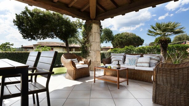 An outdoor patio with wicker furniture, a table, and a pergola overhead.