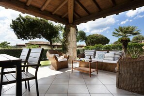 Un patio al aire libre con mobiliario de mimbre, una mesa y una pérgola.