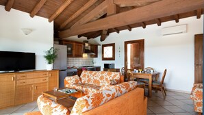 A cozy living area with a sofa, a dining table, and a kitchen in the background.