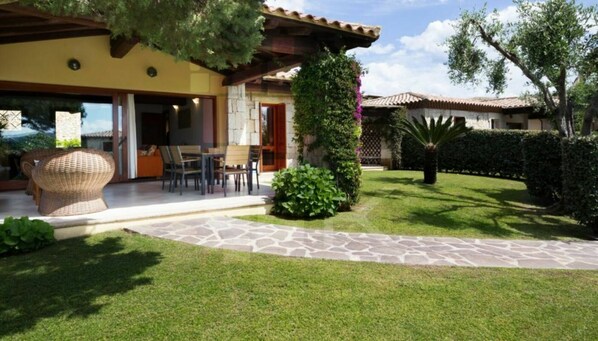 Una casa con un patio, mobiliario exterior y un jardín bien cuidado.