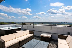 Terraza en la azotea con jacuzzi, asientos acolchados y vista al horizonte de la ciudad.