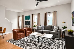A modern living room with a sofa, two armchairs, a coffee table, and a patterned rug. - 2 Nashville Homes • Hot Tubs • Sleeps Up to 24 (Nashville)