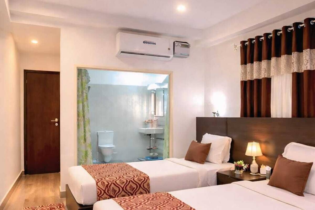 Habitación de hotel con dos camas, baño y zona de ducha.