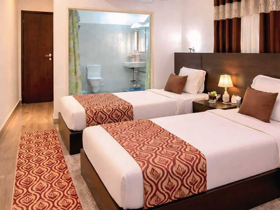 Habitación de hotel con dos camas, baño y zona de ducha.