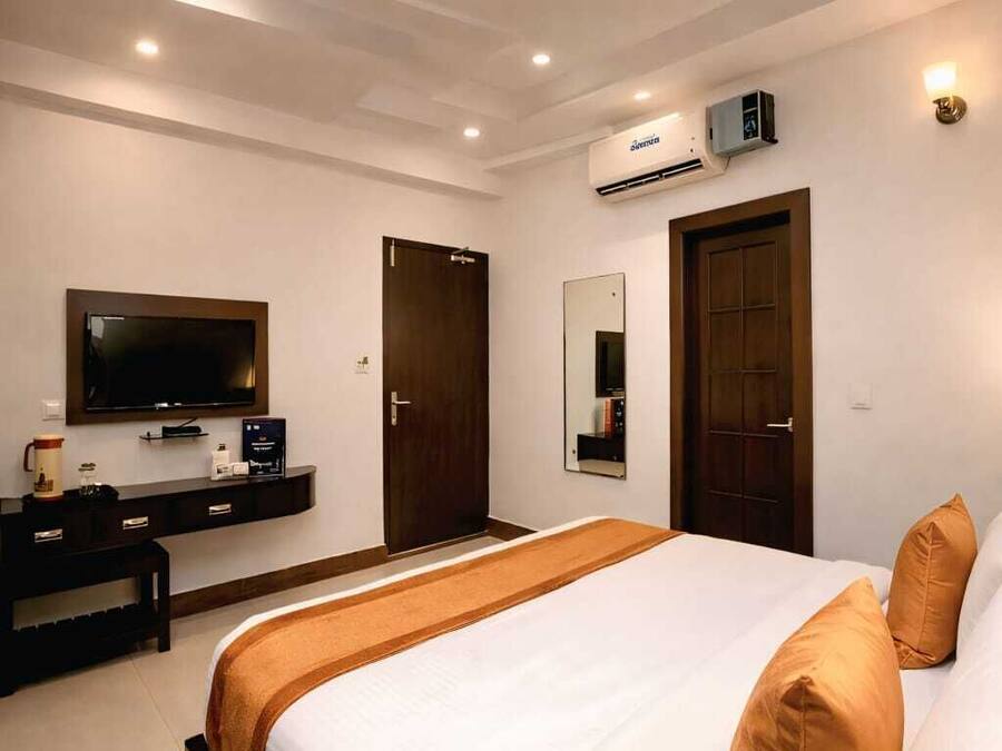 A hotel room with a bed, a TV, a desk, and a wardrobe.