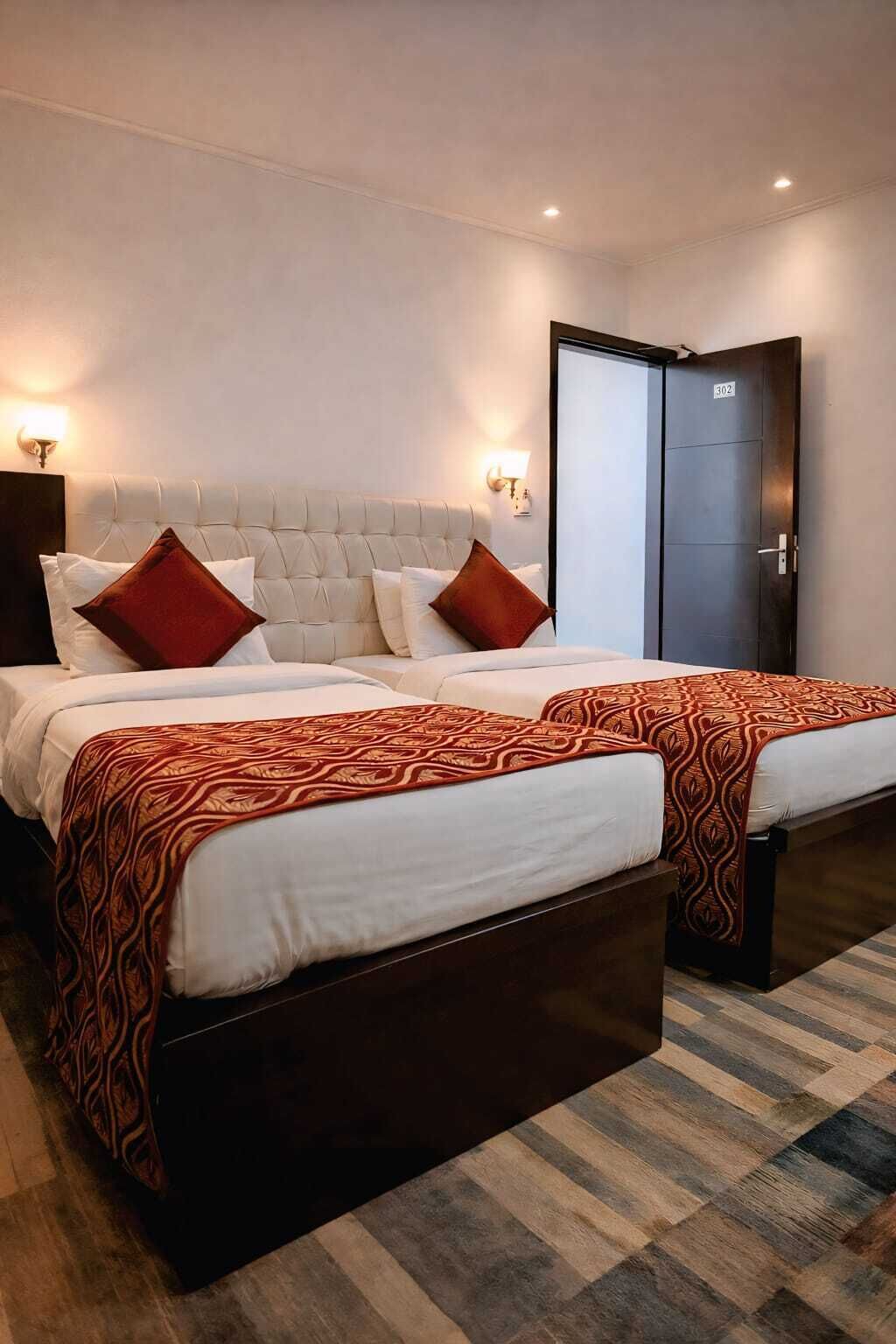 A double bed with a tufted headboard, two bedside tables, and a patterned throw blanket.