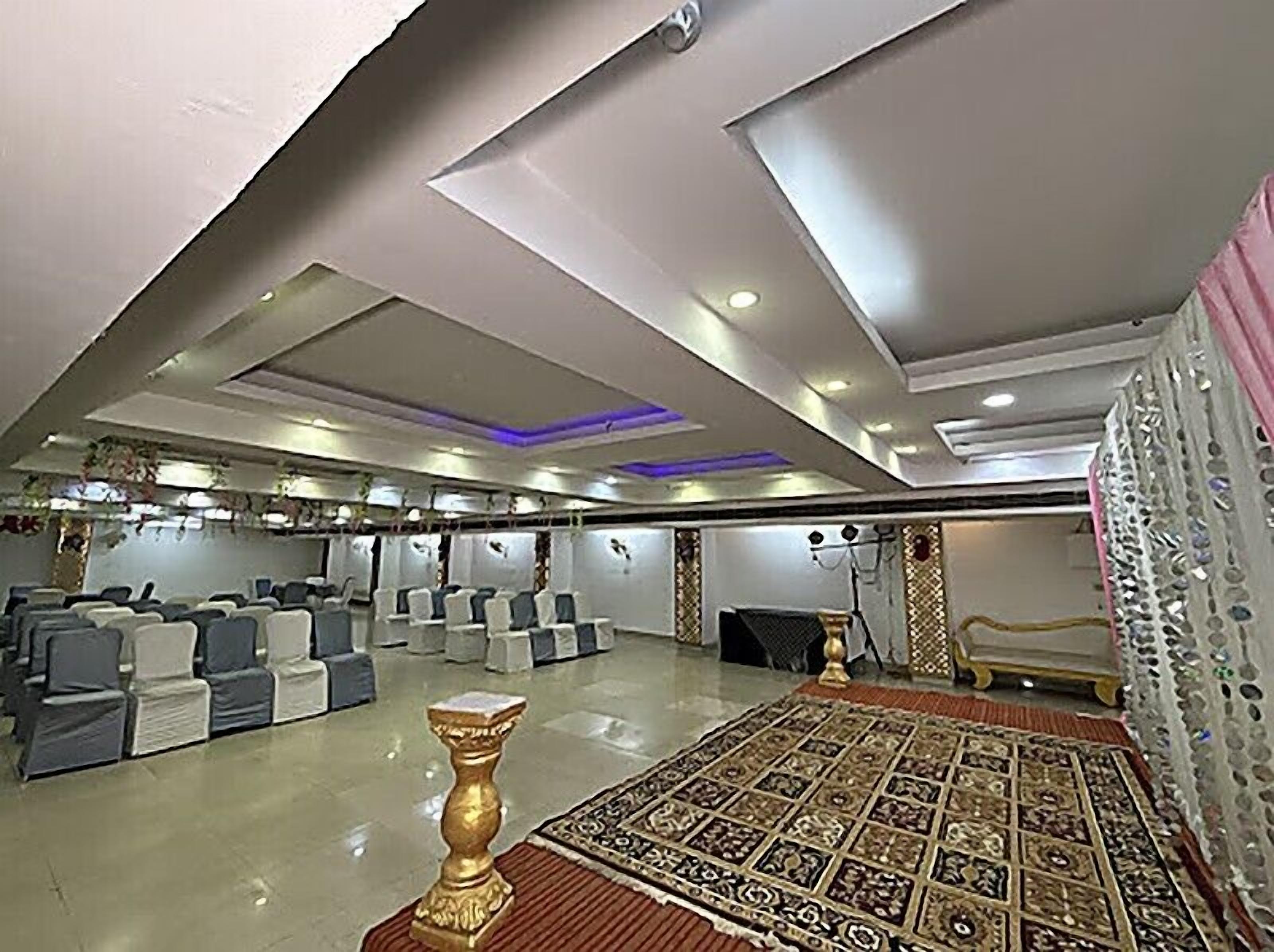 A spacious room with rows of chairs, a patterned carpet, and a decorative wall.