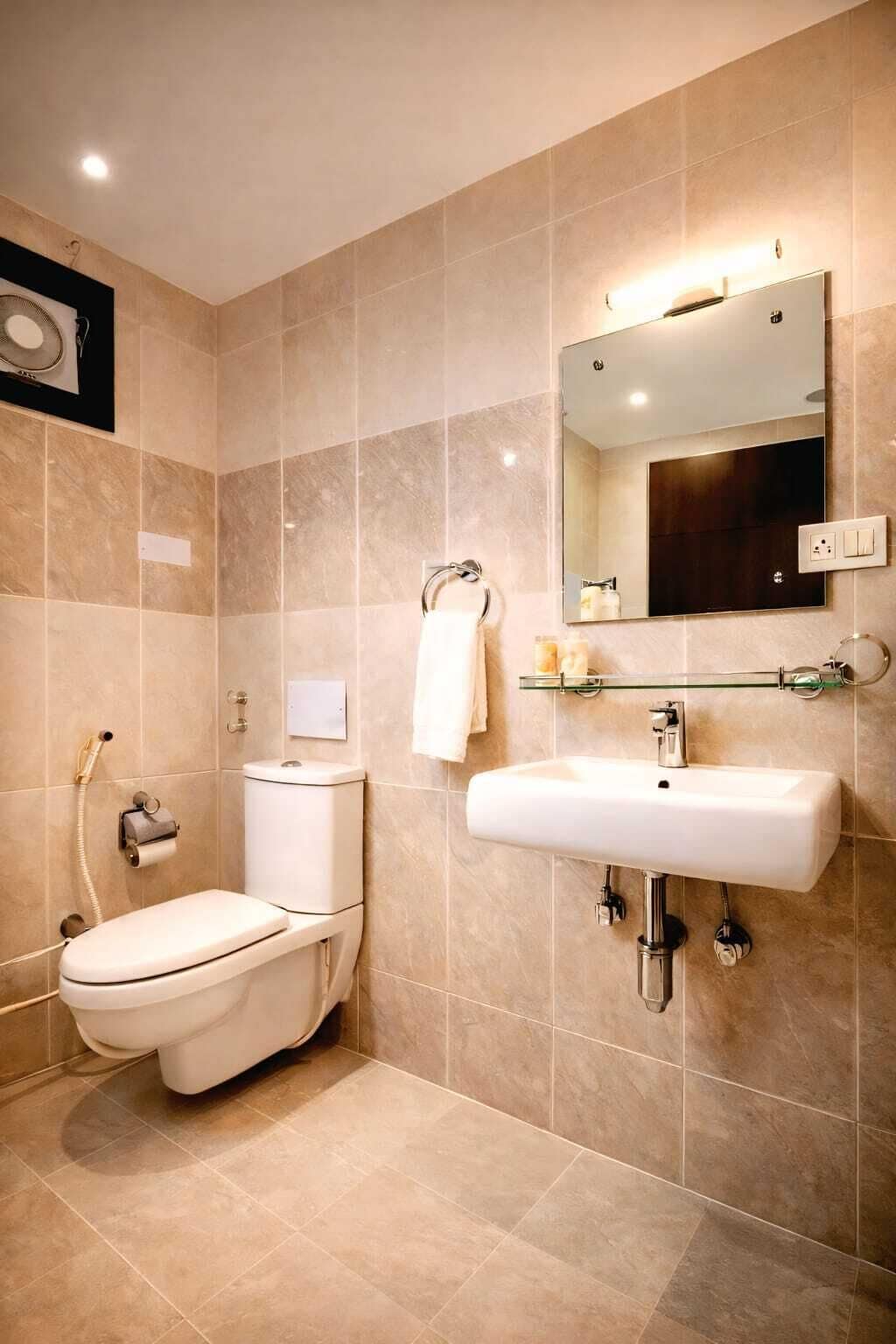 A bathroom with a toilet, sink, mirror, and shower.