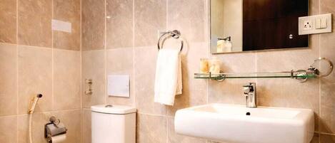 A bathroom with a toilet, sink, mirror, and shower.