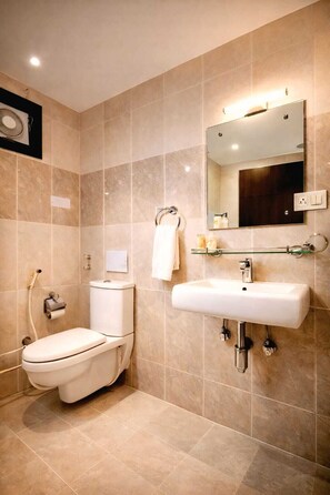 A bathroom with a toilet, sink, mirror, and shower. - Goyal Hoteliers - The Hotel Samovar (Agra)