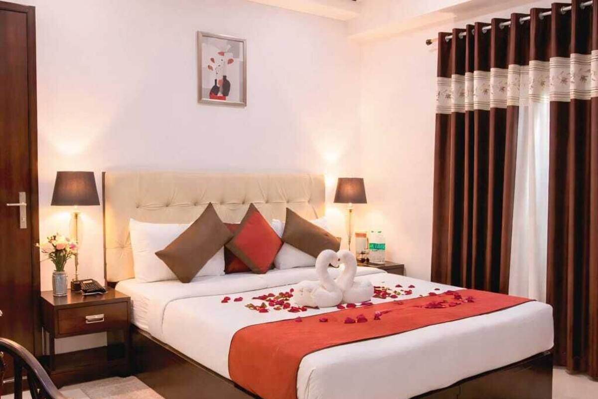 Una habitación de hotel con una cama grande, mesitas de noche, un escritorio y una silla.