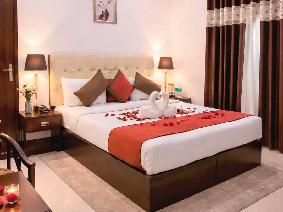 Una habitación de hotel con una cama grande, mesitas de noche, un escritorio y una silla.