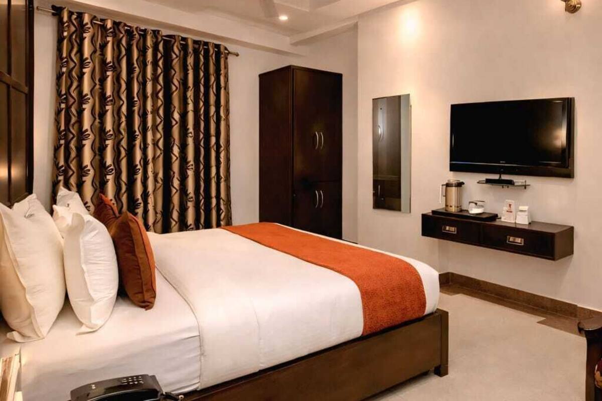 Una habitación de hotel moderna con una cama grande, un televisor de pantalla plana, un ventilador de techo y un minibar.