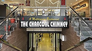 Entrada a un restaurante con un letrero que dice 'The Charcoal Chimney'.