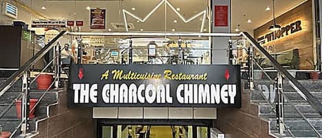 Entrada de restaurante com uma placa que diz 'The Charcoal Chimney'.