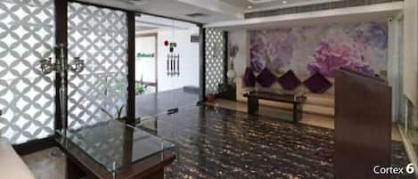 Un lobby moderno con una mesa de centro de vidrio, un sofá y un cuadro abstracto grande en la pared.