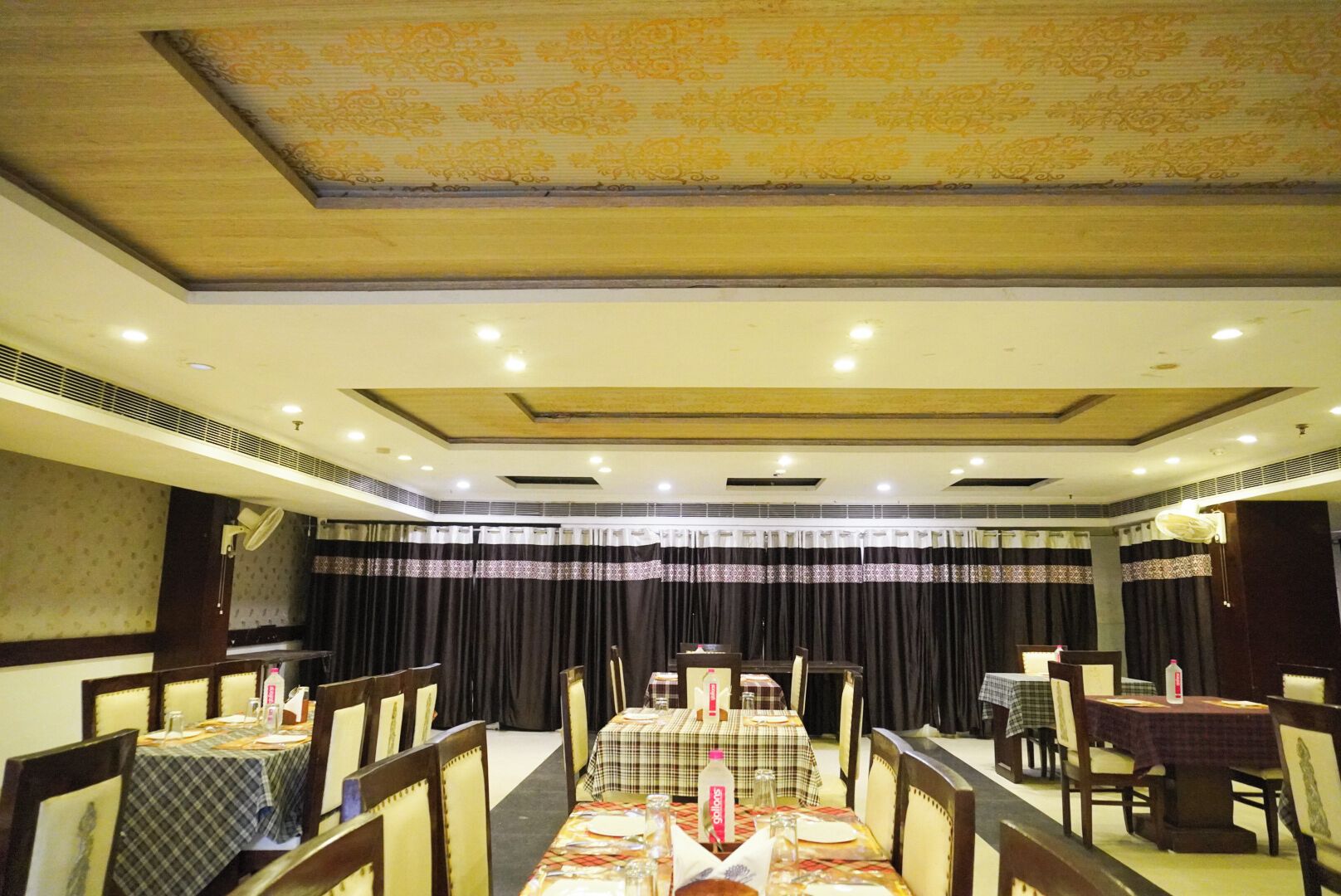 A dining area with tables set for service, a stage, and a curtain backdrop.